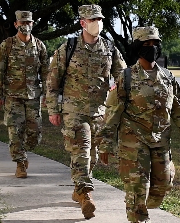 Soldiers wearing face masks walk in a line.