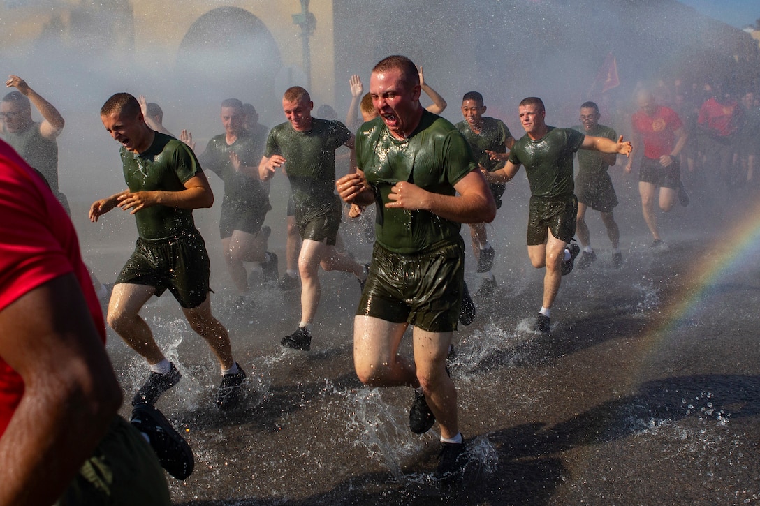 A group of Marines run along a roadway.