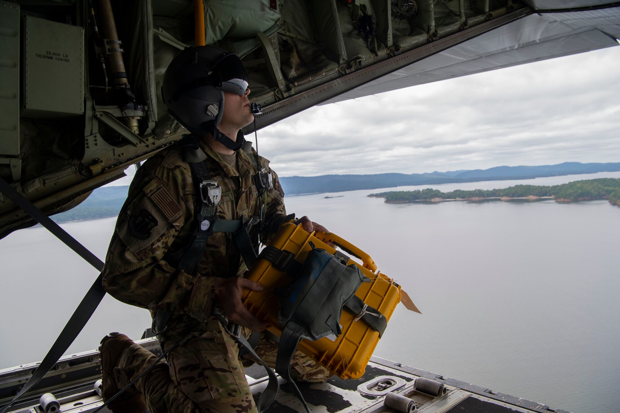 A loadmaster prepares for an airdrop over a lake.