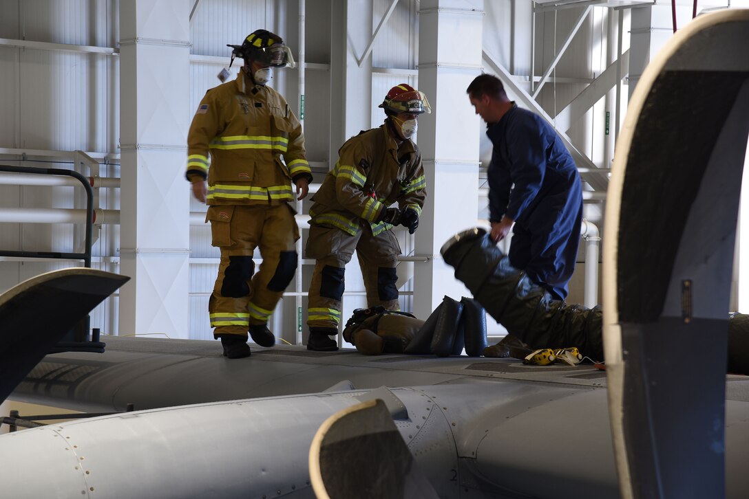 Firefighters Colby Fairfax and David Cleland, 81st Civil Engineering Squadron, approach Tech. Sgt. David Deschenes, 403rd Maintenance Squadron fuel systems specialist, and the extracted 'Rescue Randy' from the fuel tank of the C-130J Super Hercules during a confined space extraction exercise Sept. 30 at Keesler Air Force Base, Miss. This exercise is a combined effort of the 403rd MXS and the  and the 81st Training Wing's Fire Department to ensure that both the fuel systems specialists and the emergency responders are able to safely extract patients from any confined space at any time. (U.S. Air Force photo by Jessica L. Kendziorek)