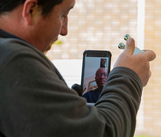 Abraham Egley, a member of Headquarters and Service Battalion, U.S. Marine Corps Forces Command, Fleet Marine Force Atlantic, Facility Maintenance Team, video-calls Carlos Johnson, the Senior Maintenance Executive (SME) of Facility Maintenance Team, for assistance while repairing the heating, ventilation, and air conditioning system (HVAC)  May 13, 2020, at Hopkins Hall Gym, on Camp Elmore in Norfolk, Virginia.