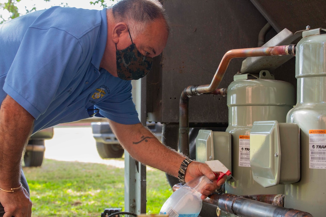 Terrance Henry, a member of U.S. Marine Corps Forces Command, Fleet Marine Force Atlantic, Facility Maintenance Team, sprays bubble water on the pipes of the heating, ventilation, and air conditioning system (HVAC) during an air pressure test, May 13, 2020, at Hopkins Hall Gym, on Camp Elmore in Norfolk, Virginia.