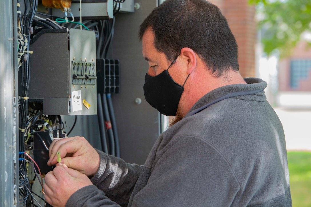 Abraham Egley, a member of, U.S. Marine Corps Forces Command, Fleet Marine Force Atlantic, Facility Maintenance Team, connects the wires of the heating, ventilation, and air conditioning system (HVAC) May 13, 2020, at Hopkins Hall Gym, on Camp Elmore in Norfolk, Virginia.
