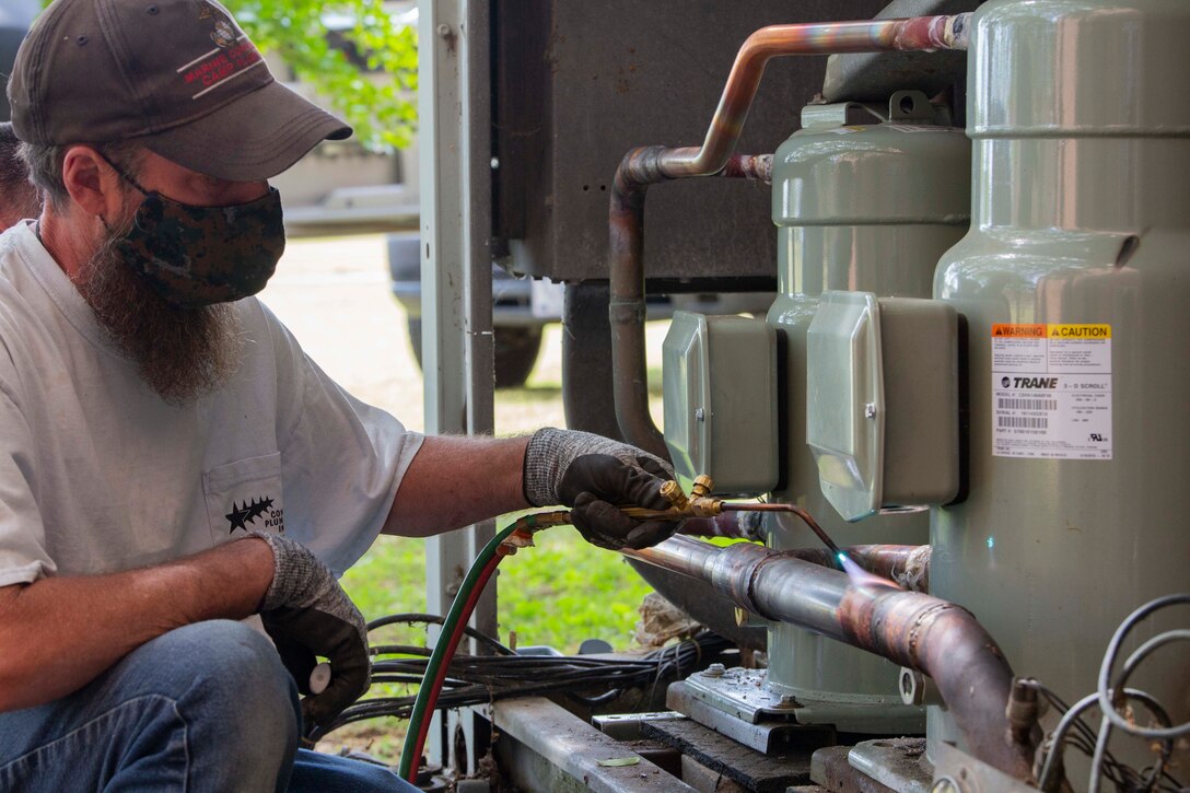 Matt Greer, a member of U.S. Marine Corps Forces Command, Fleet Marine Force Atlantic, Facility Maintenance Team, brazes the pipes of the heating, ventilation, and air conditioning system (HVAC) May 13, 2020, at Hopkins Hall Gym, on Camp Elmore in Norfolk, Virginia.
