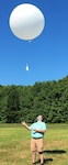 IMAGE: DAHLGREN, Va. - Henry Wilson - a STEM (science, technology, engineering and mathematics) student employment program intern - launches a weather balloon to record a vertical optical turbulence profile in support of a collaborative research project combining the Navy’s next-generation laser weapons with maritime environmental challenges. Dr. Evan Bates - a Naval Surface Warfare Center Dahlgren Division systems engineer who leads the High Energy Laser Measurement Support Laboratory - hopes to take the instruments used for optical turbulence measurements and incorporate them into shipboard lasers in the future. “You want to be able to get a real-time measurement with a single-ended system, because if we can get that we can look at the environment and evaluate the atmospheric effects on laser transmission to the target," said Bates. “That’s the end goal of optical turbulence instrumentation.” (U.S. Navy photo/Released)