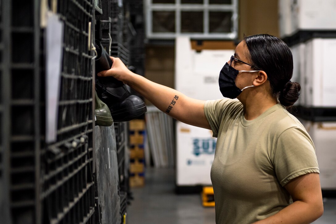 A photo of an Airman grabbing boots from a bin