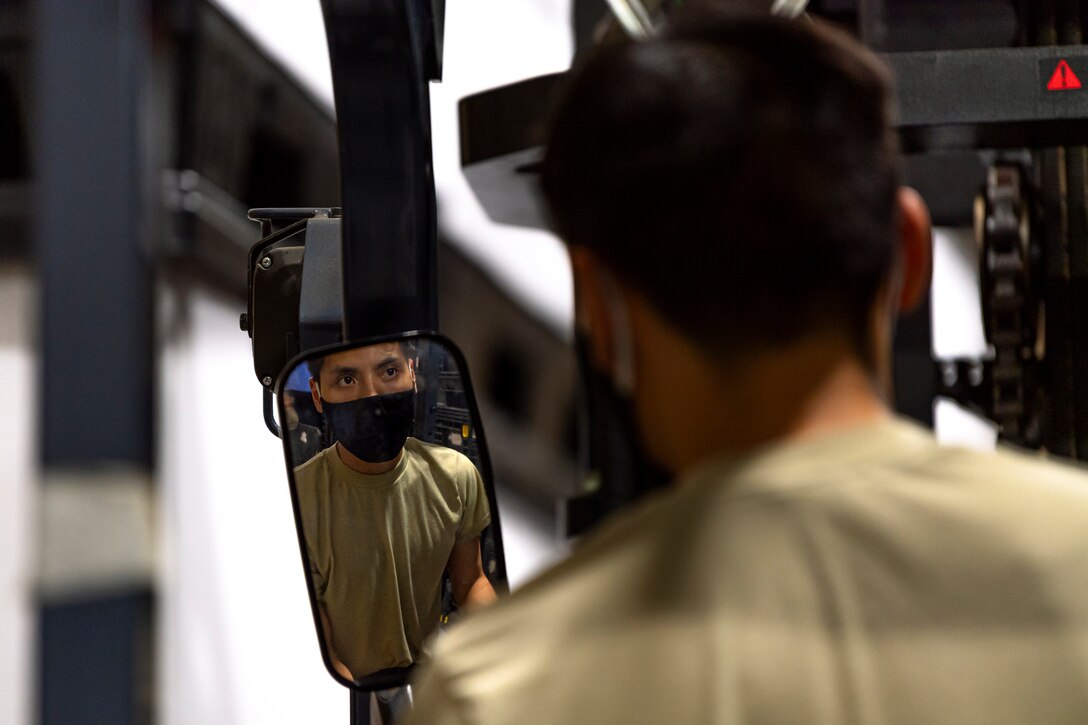 A photo of an Airman looking at a box on a forklift