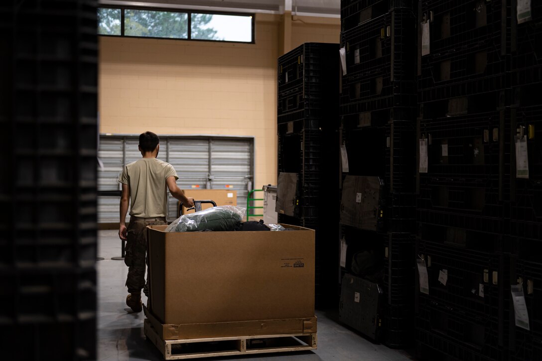 A photo of an Airman pulling a cart with a box of gear bags
