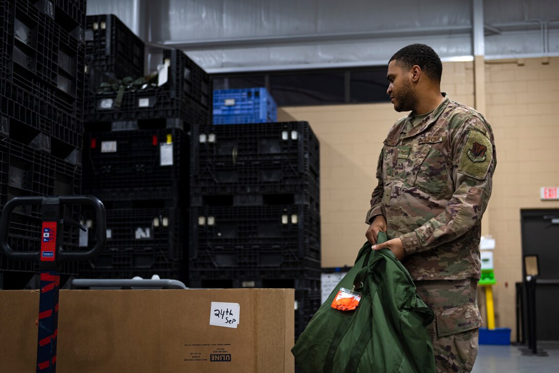 A photo of an Airman holding a bag of individual protective equipment