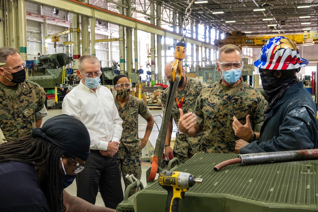 (Left) Robert “Chip” Schwartz, Manager Production Plant Barstow, Marine Depot Maintenance Command, looks on as Maj. Gen. Joseph F. Shrader, commanding general, Marine Corps Logistics Command, talks with Alton Deshazor, heavy mobile equipment mechanic, about repairs on a Light Armored Vehicle, during his visit to PPB, Sept. 29.