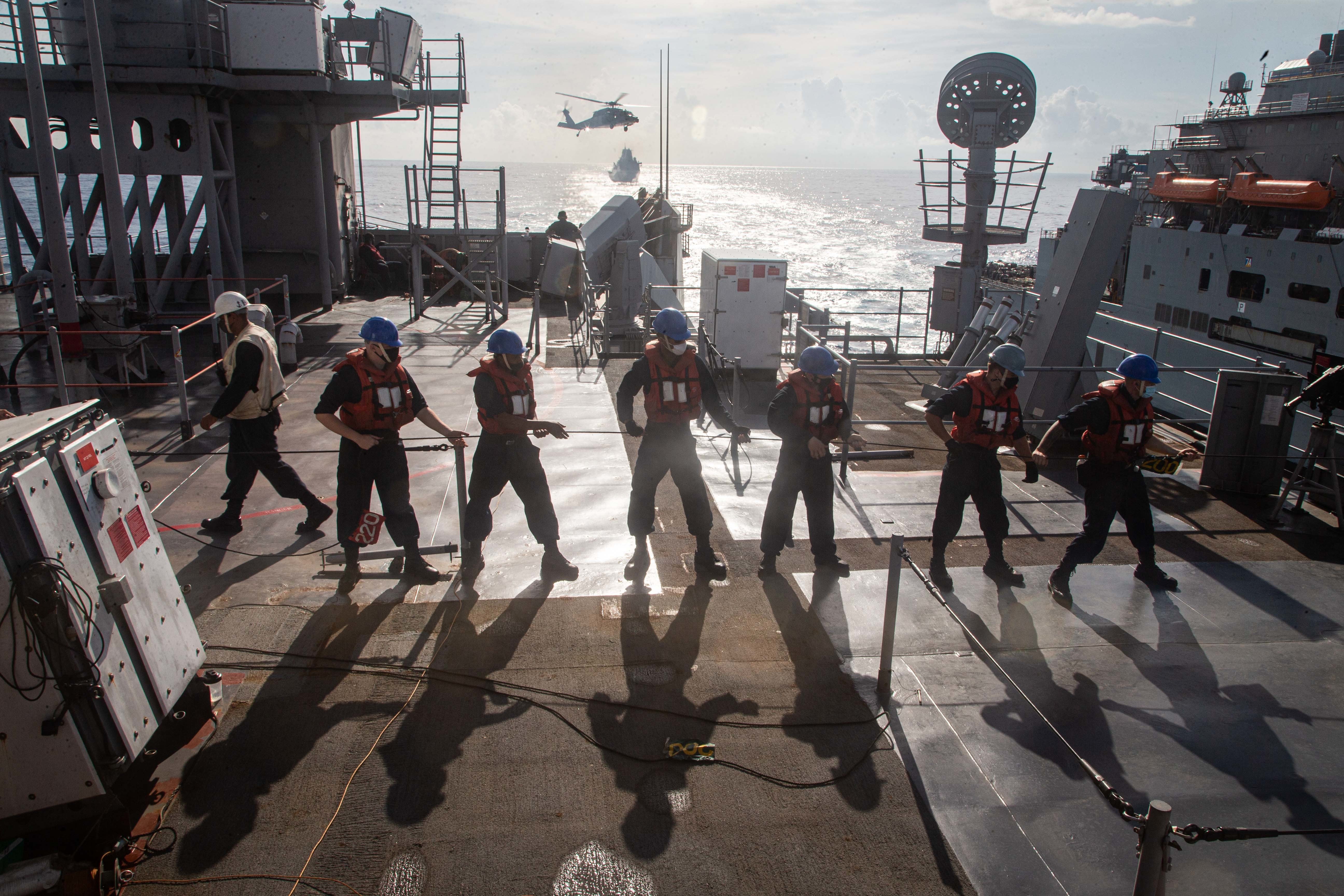 Sailors embarked on dock landing ship USS Germantown (LSD 42) handle a line during a replenishment-at-sea  with the dry cargo ship USNS Charles Drew (TAKE 10) .