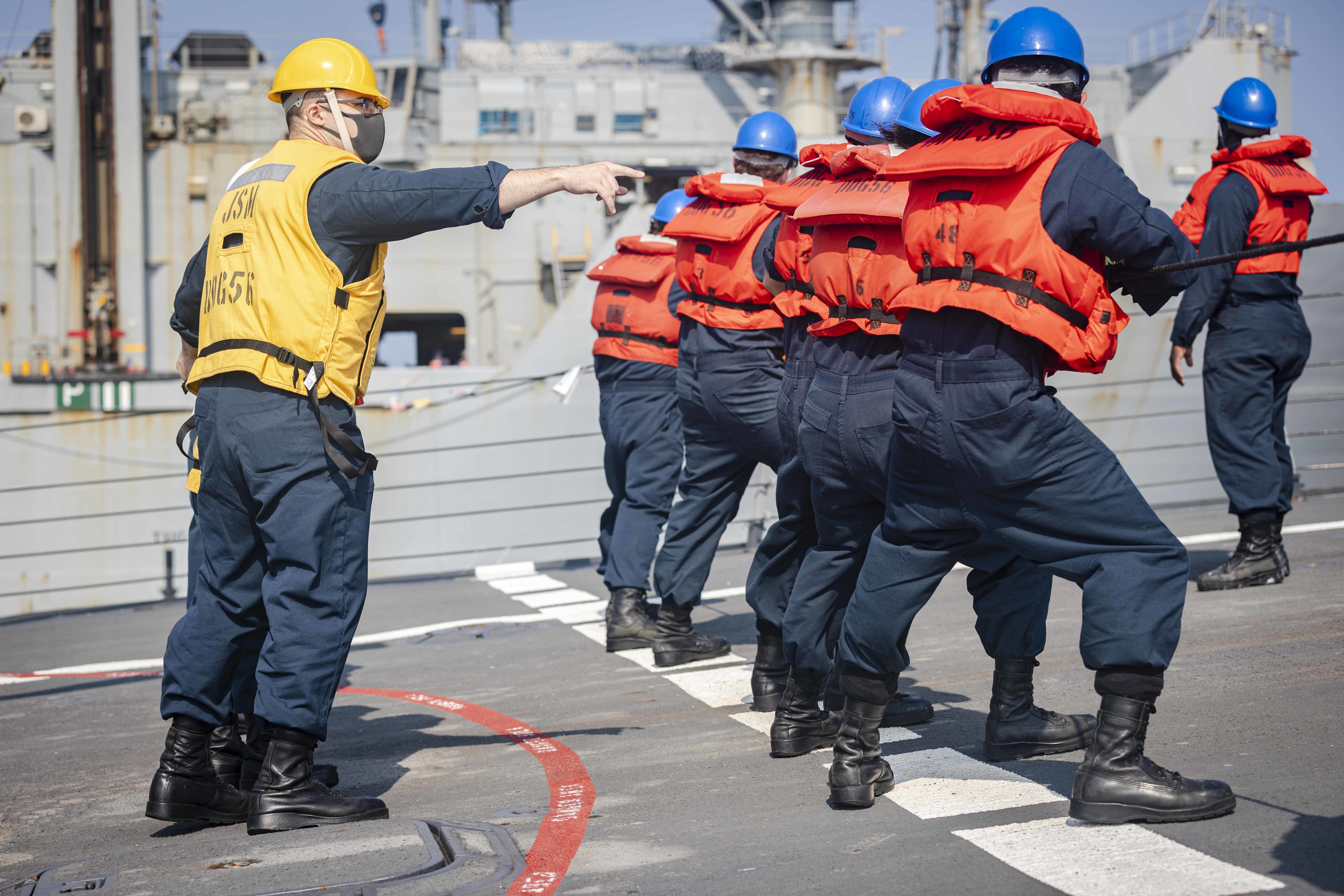 Chief Intelligence Specialist Justin Ortega, left, from Kansas City, Mo., commands line handlers to "heave" on the phone and distance line on the foc's'le aboard the Arleigh Burke-class guided-missile destroyer USS John S. McCain (DDG 56) during a replenishment-at-sea with the Lewis and Clark-class dry cargo ship USNS Washington Chambers (T-AKE-11).