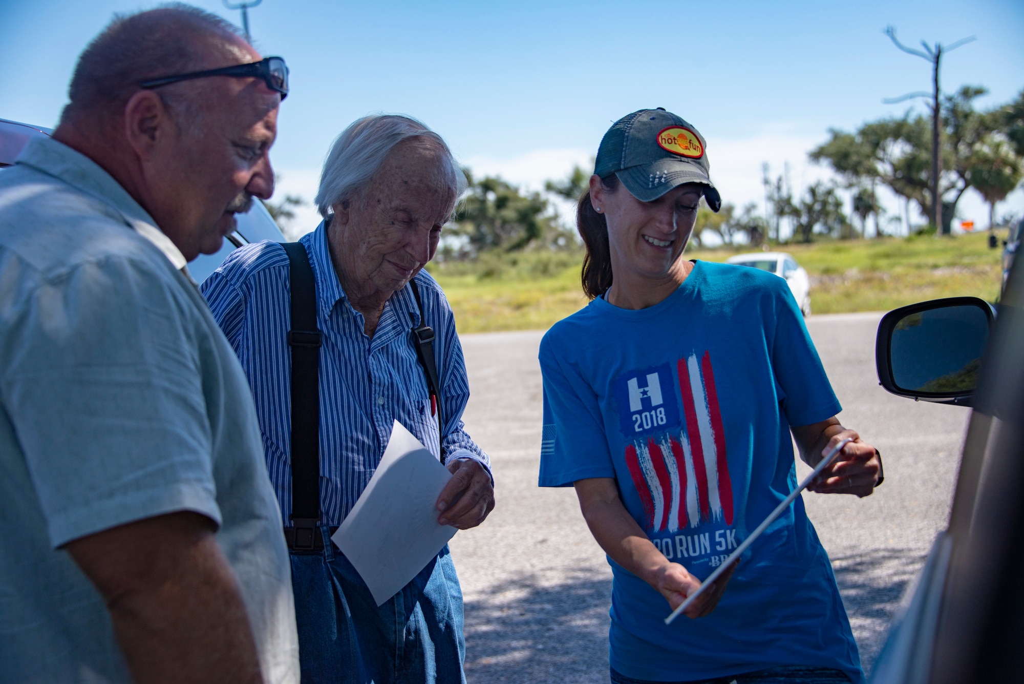 three people standing, looking at a photo