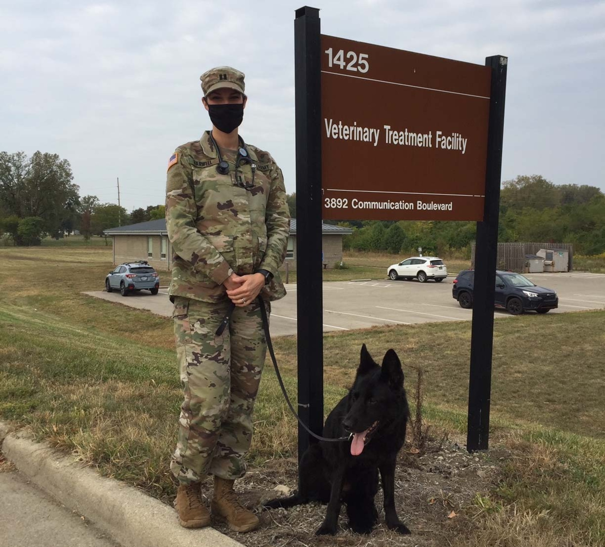 Army Capt. (Dr.) Casey Barwell, the new veterinary branch chief at Wright-Patterson Air Force Base, stands with Suzy, a 12-year-old retired military working dog she and her husband adopted several years ago, in front of the Veterinary Treatment Facility. (Skywrighter photo/Amy Rollins)
