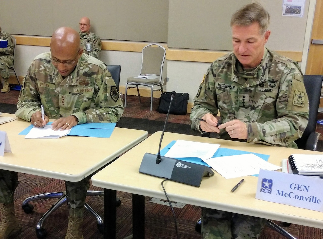 Two military officers sign agreements.