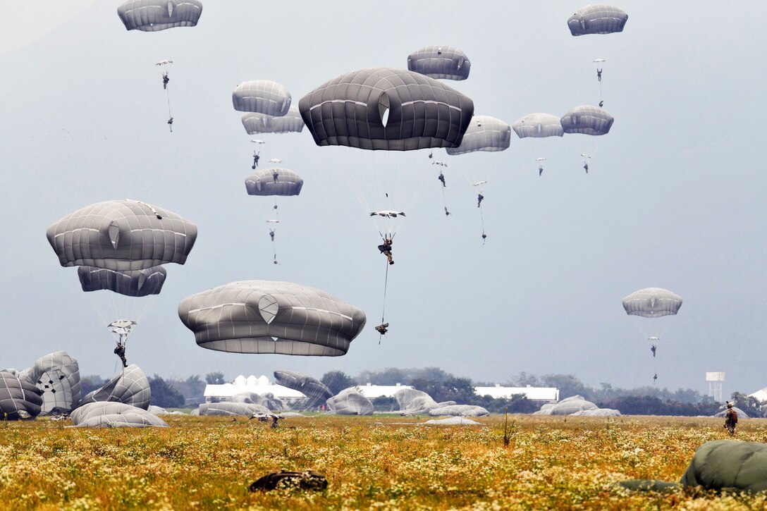 Soldiers free fall wearing parachutes.