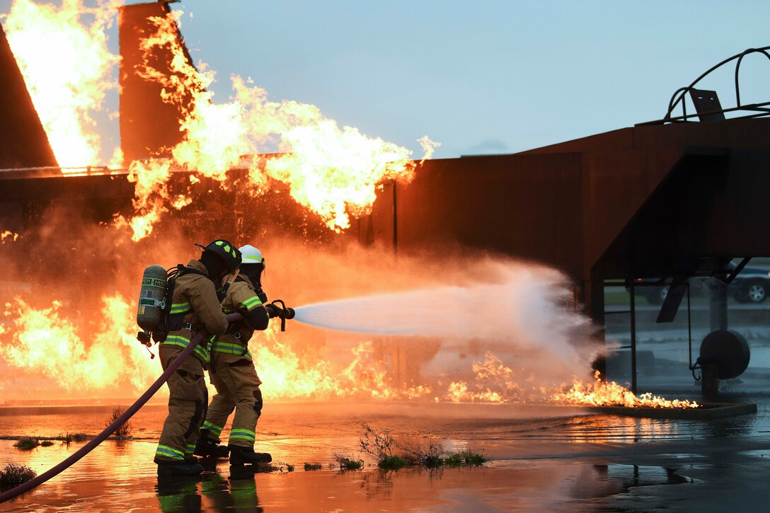 Airmen use a water hose to put out a fire during training.