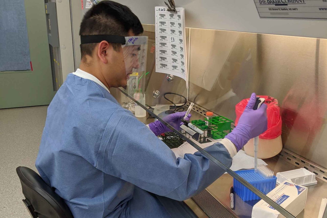 An Air Force officer, wearing PPE, tests COVID-19 samples in a lab.