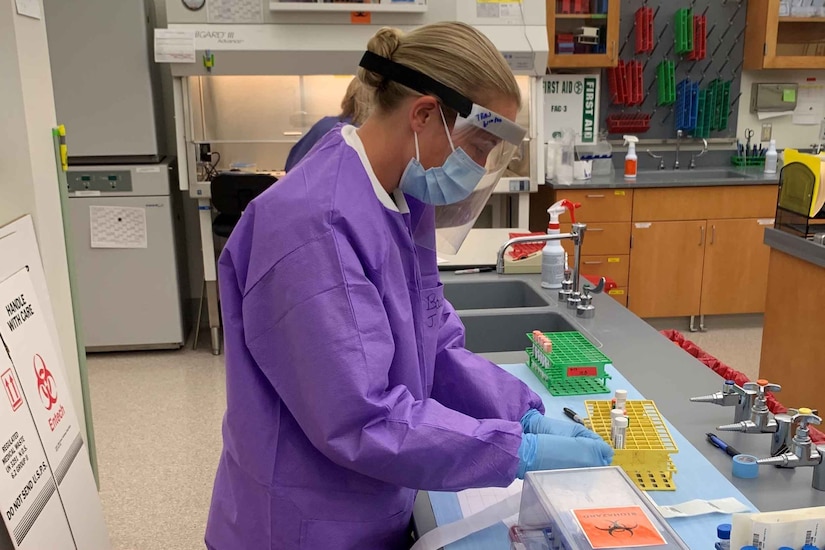 An Army officer, wearing PPE, tests COVID-19 samples in a lab.