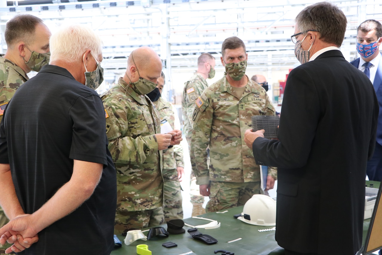 A man examines a long, thin piece of plastic as other men stand nearby; all are wearing face masks.