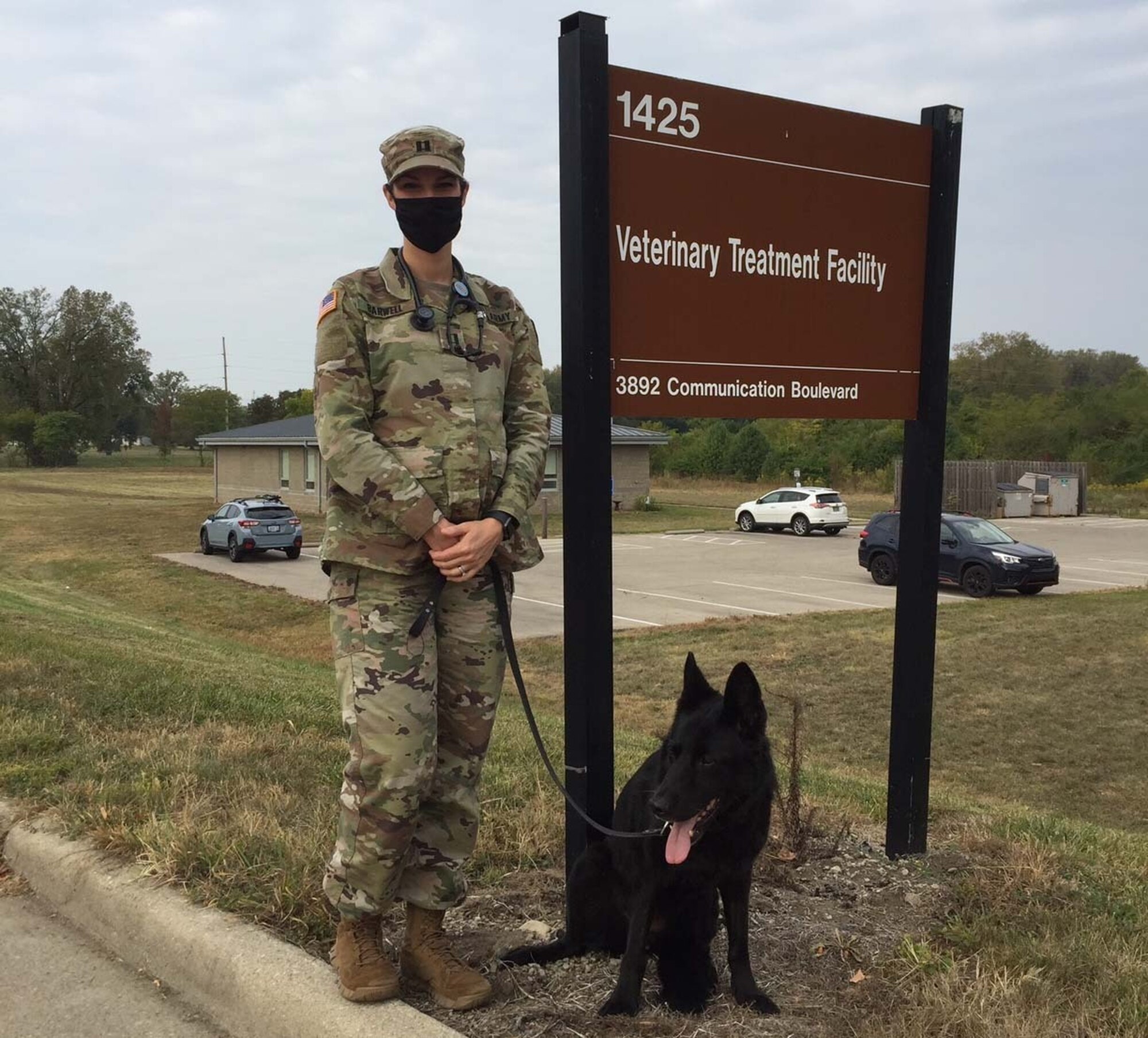 Army Capt. (Dr.) Casey Barwell, the new veterinary branch chief at Wright-Patterson Air Force Base, stands with Suzy, a 12-year-old retired military working dog she and her husband adopted several years ago, in front of the Veterinary Treatment Facility. (Skywrighter photo/Amy Rollins)