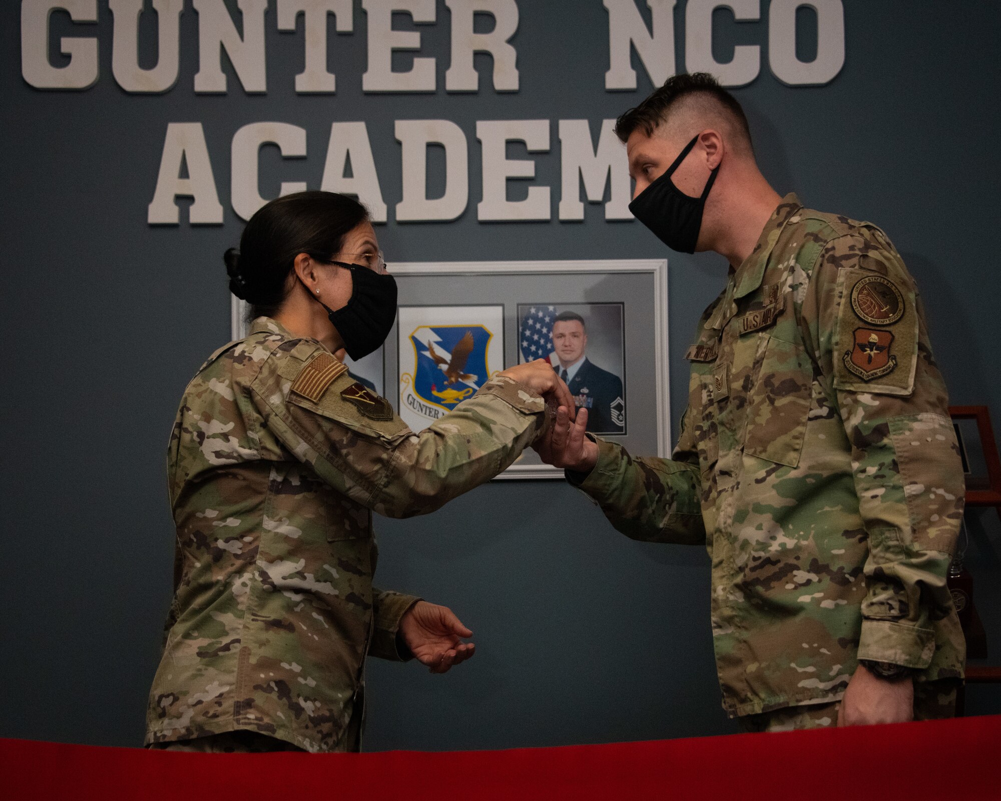 Col. Kathryn Brown, Thomas N. Barnes Center for Enlisted Education commander, presents a coin to Tech. Sgt. Jonathan Kertulis
