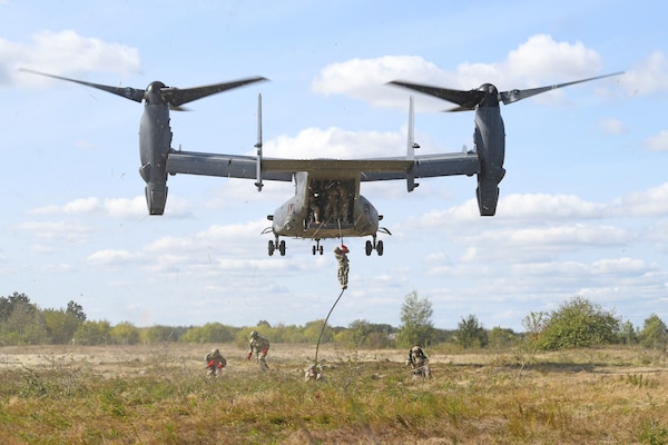 Military descend by rope from hovering aircraft.