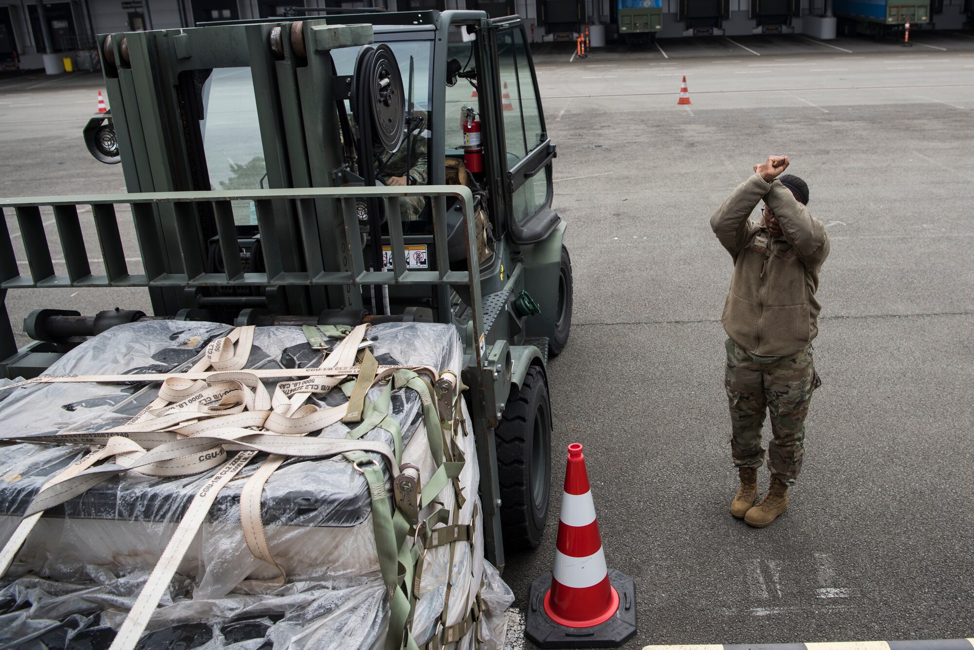 U.S. Air Force Senior Airman Pascal Borgman, 721st Aircraft Maintenance Squadron communication navigation system journeyman, signals a 10k forklift driver during a multi-capable Airmen lift-and-shift training.