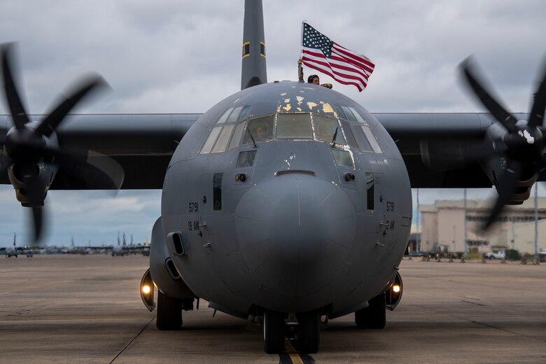 An Airman waves a flag out the top of a C-130.