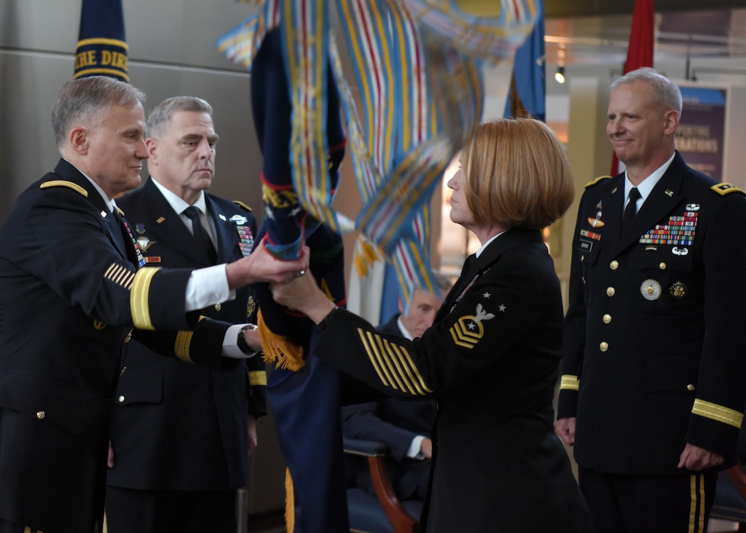 Former Defense Intelligence Agency Director Lt. Gen. Robert Ashley Jr (front left) hands the DIA flag to DIA Command Senior Enlisted Leader Command Master Chief Laura Nunley during the DIA Change of Directorship Ceremony. Chairman of the Joint Chiefs of Staff Gen. Mark Milley (back left) presided over the ceremony in which Lt. Gen. Scott Berrier (right) became the 22nd director of DIA.