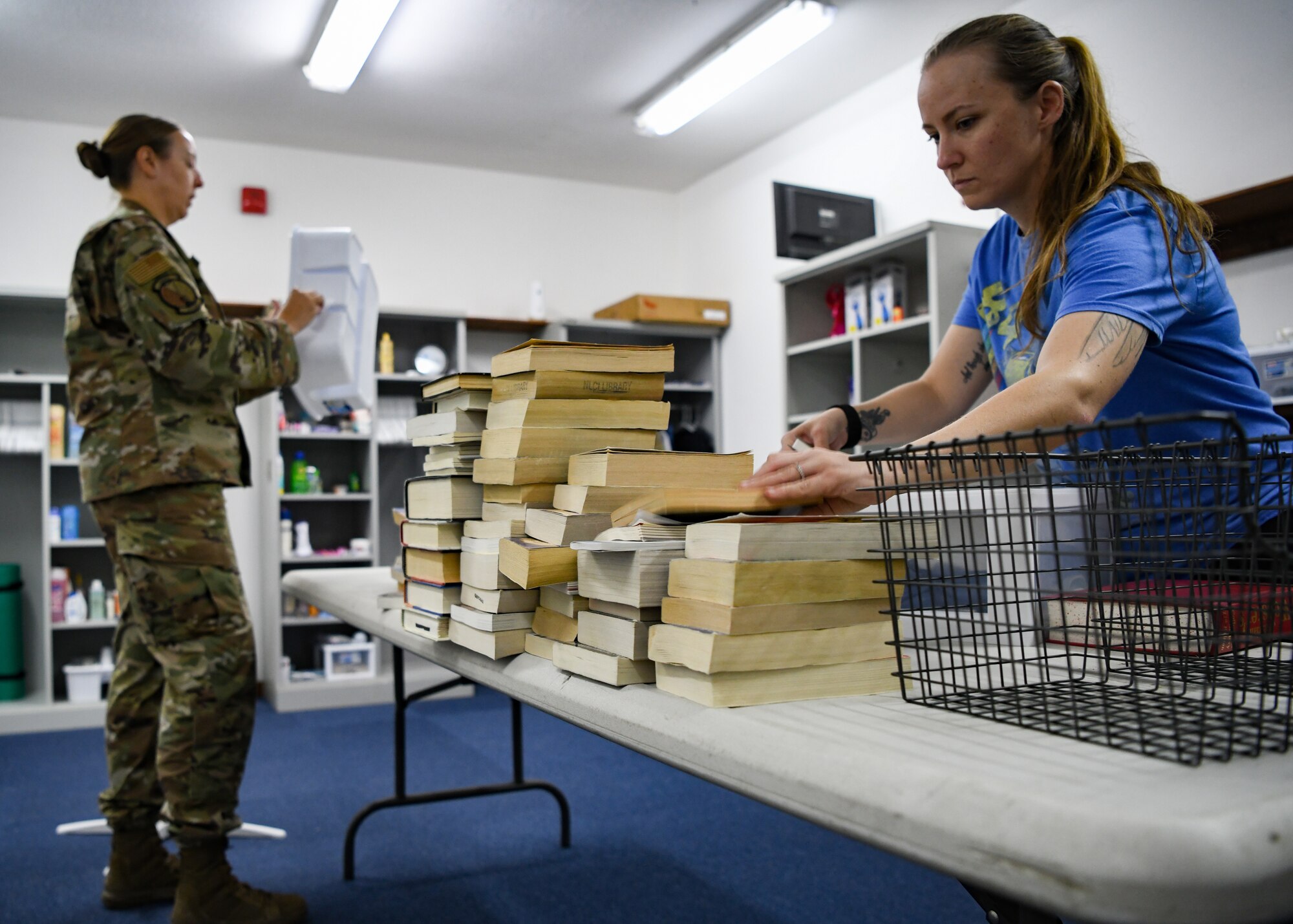 Tech. Sgt. Janae Steude, 727th Expeditionary Air Control Squadron commander’s executive assistant and Enduring 5/6 member, cleans a shower caddy while Senior Airman Shawndae Wilkins, 380th Expeditionary Contracting Squadron contracting officer and First Four member, sorts books for the new Airman’s Attic at Al Dhafra Air Base, United Arab Emirates, Oct. 3, 2020.