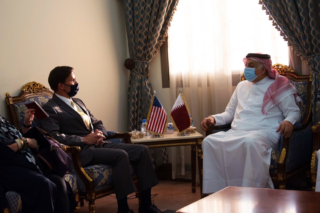 Defense Secretary Dr. Mark T. Esper  sits in a chair and speaks with another man.