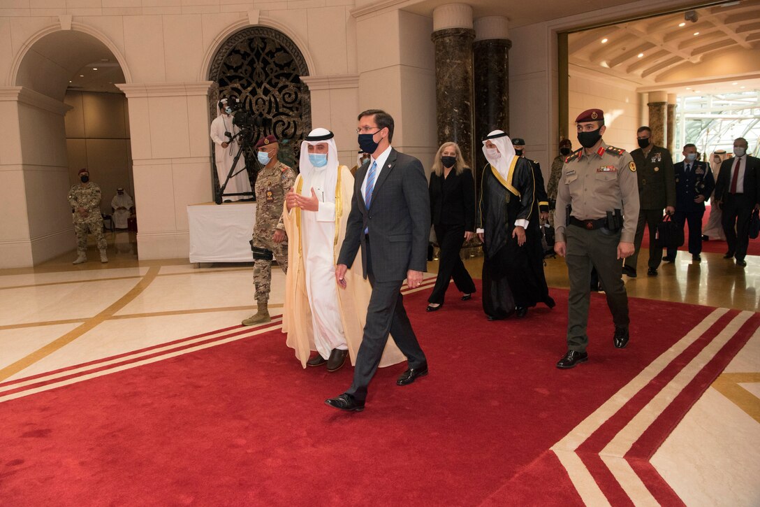 Defense Secretary Dr. Mark T. Esper walks with a group of people on a red carpet.