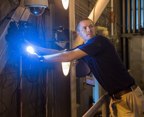 Seth Beaman, a Naval Air Systems Command aeropropulsion test analyst, aims a light mounted alongside a high-speed camera at an aircraft engine, Sept. 1, 2020, in the sea-level test cell SL-1 at Arnold Air Force Base, Tenn. The camera, combined with software, allows for the observation and measurement of vibrations. Beaman is studying the potential for its use as an analysis tool for engine testing. (U.S. Air Force photo by Jill Pickett)