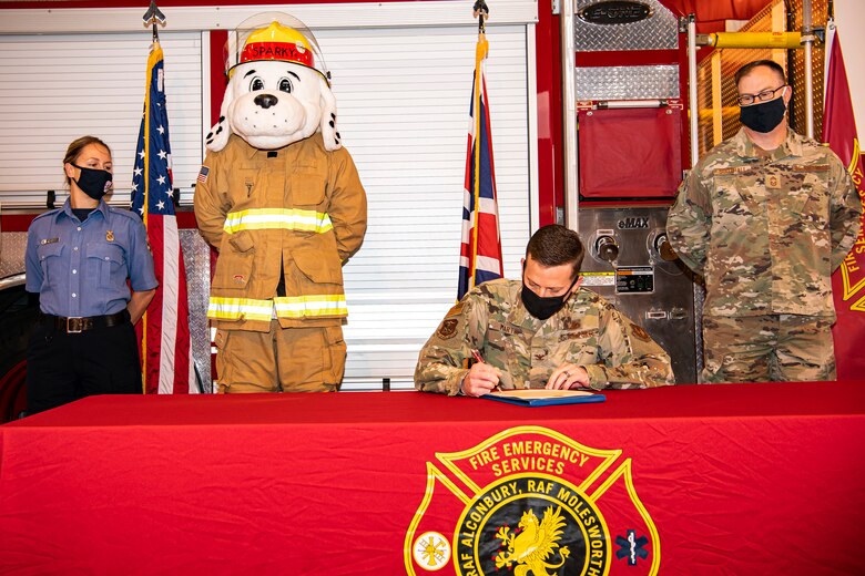 U.S. Air Force Col. Richard Martin, center right, 423rd Air Base Group commander, signs a fire safety proclamation at RAF Alconbury, England, Oct. 5, 2020. Martin proclaimed Oct.5-9 as Fire Prevention week, which is designed to honor the sacrifices of our firefighters and teach fire safety to others. (U.S. Air Force photo by Senior Airman Eugene Oliver)