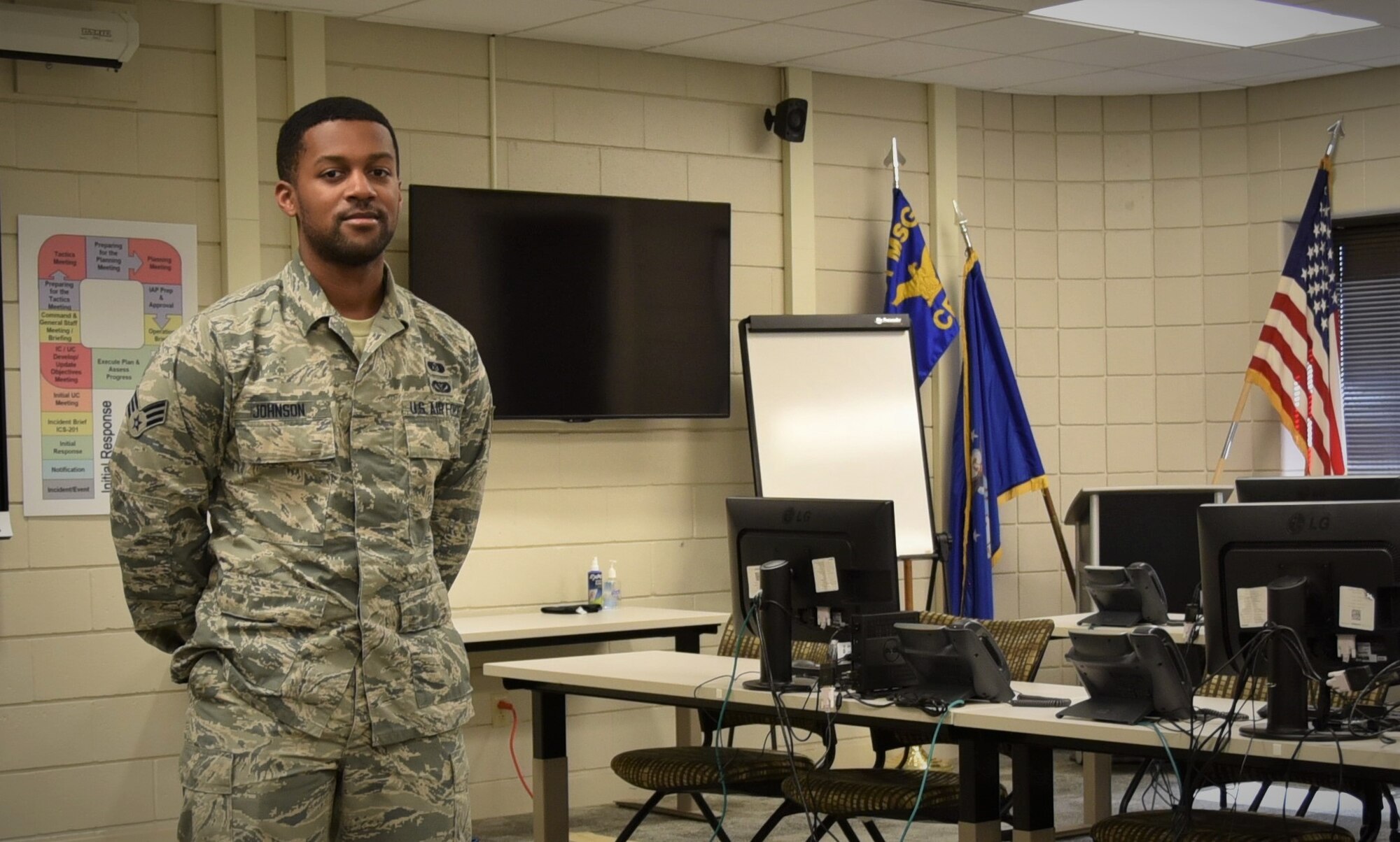 U.S. Air Force Senior Airman Lawrence Johnson, 301st Fighter Wing Civil Engineer Squadron emergency management specialist, stands in the emergency operations center at U.S. Naval Air Station Joint Reserve Base Fort Worth, Texas. Johnson, a Chickasha, Okla. native, credits his training and his team for the successful wing navigation through this pandemic. (U.S. Air Force photo by Senior Airman Kedesha Pennant)