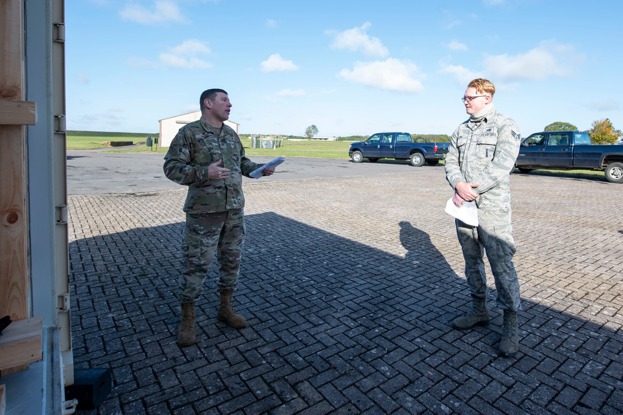 U.S. Air Force Senior Airman Ian Fike, right, 420th Munitions Squadron conventional maintenance crew chief, shows Col. Kurt Wendt, left, 501st Combat Support Wing commander, regulations and instructions to build wooden blocking and bracing to secure munitions during shipment, during a visit to RAF Welford, England, Oct. 1, 2020. Wendt visited 420th MUNS to meet with the Airmen and to learn more about their new mission capabilities. (U.S. Air Force photo by Senior Airman Jennifer Zima)