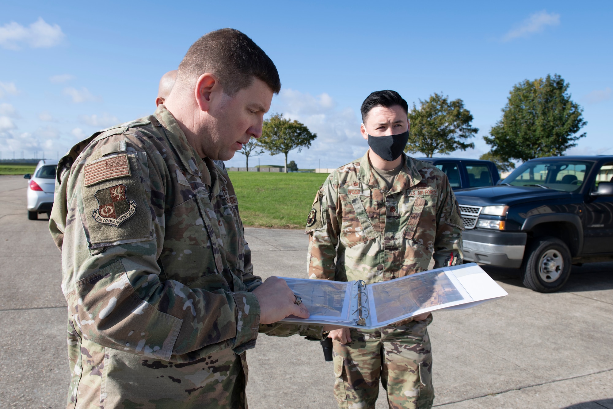 U.S. Air Force Col. Kurt Wendt, left, 501st Combat Support Wing commander, and Maj. Christopher Wood, right, 420th Munitions Squadron commander, look at photographs of the vehicle processing area where wooden support structures are built for the explosive International Standards Organization (ISO) shipping containers, during a visit to RAF Welford, England, Oct. 1, 2020. Wendt visited 420th MUNS to meet with the Airmen and to learn more about their new mission capabilities. (U.S. Air Force photo by Senior Airman Jennifer Zima)