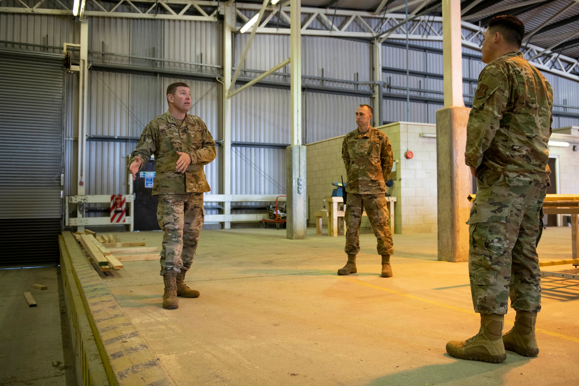 U.S. Air Force Col. Kurt Wendt, left, 501st Combat Support Wing commander, and Maj. Christopher Wood, right, 420th Munitions Squadron commander, Tech. Sgt. Brandon Mullennix, center, 420th MUNS conventional munition shop chief, tour the vehicle processing area where wooden support structures are built for the explosive International Standards Organization (ISO) shipping containers, during a visit to RAF Welford, England, Oct. 1, 2020. Wendt visited 420th MUNS to meet with the Airmen and to learn more about their new mission capabilities. (U.S. Air Force photo by Senior Airman Jennifer Zima)