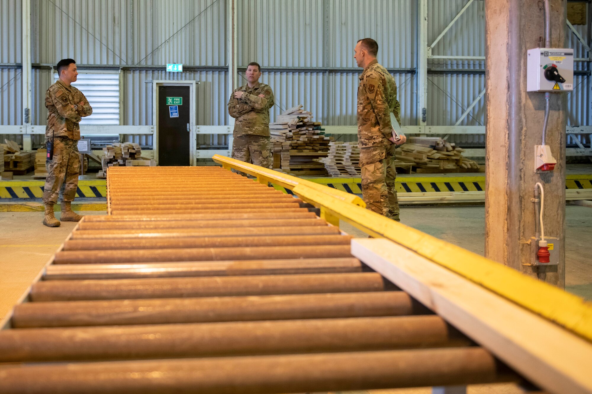 U.S. Air Force Col. Kurt Wendt, center, 501st Combat Support Wing commander, and Maj. Christopher Wood, left, 420th Munitions Squadron commander, Tech. Sgt. Brandon Mullennix, right, 420th MUNS conventional munition shop chief, tour the vehicle processing area where wooden support structures are built for the explosive International Standards Organization (ISO) shipping containers, during a visit to RAF Welford, England, Oct. 1, 2020. Wendt visited 420th MUNS to meet with the Airmen and to learn more about their new mission capabilities. (U.S. Air Force photo by Senior Airman Jennifer Zima)