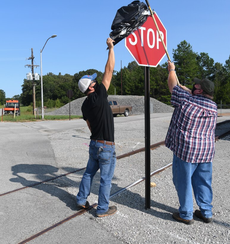 Laborers Danny Smartt, left, and Kelvin Sweeton uncover one of four stop signs installed at an intersection near the J-4 Rocket Motor Test Facility at Arnold Air Force Base, Tenn., Sept. 11, 2020. The signs were uncovered after craftsmen were notified of their installation during toolbox meetings. (U.S. Air Force photo by Jill Pickett)