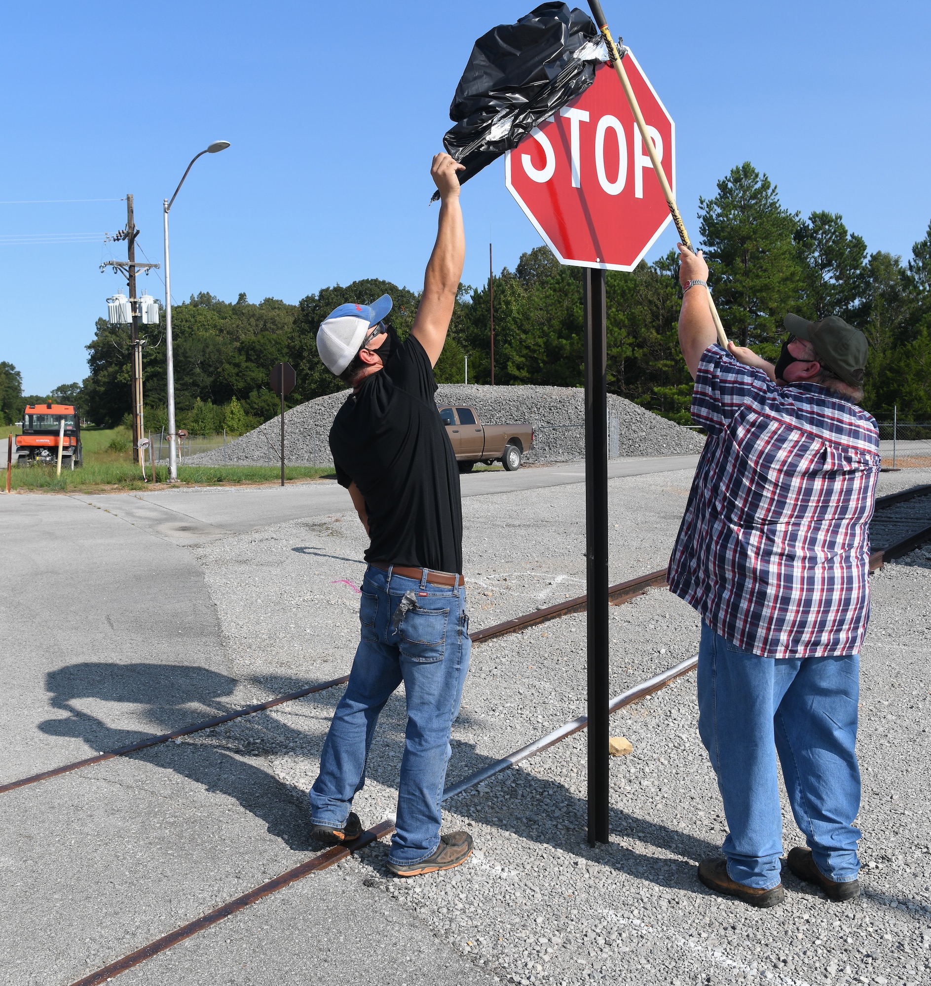 Laborers Danny Smartt, left, and Kelvin Sweeton uncover one of four stop signs installed at an intersection near the J-4 Rocket Motor Test Facility at Arnold Air Force Base, Tenn., Sept. 11, 2020. The signs were uncovered after craftsmen were notified of their installation during toolbox meetings. (U.S. Air Force photo by Jill Pickett)
