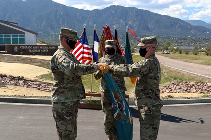Army Col. Mike Hatfield, the commander of the 100th Missile Defense Brigade, right, and Lt. Col. Michael Lane, the commander of the 117th Space Battalion, unfurl the colors of the 117th Space Battalion during a ceremony at Fort Carson, Colorado, to signify a command relationship change. The 117th is now assigned to the 100th for administrative and operational command and control as part of a larger Colorado Army National Guard realignment.