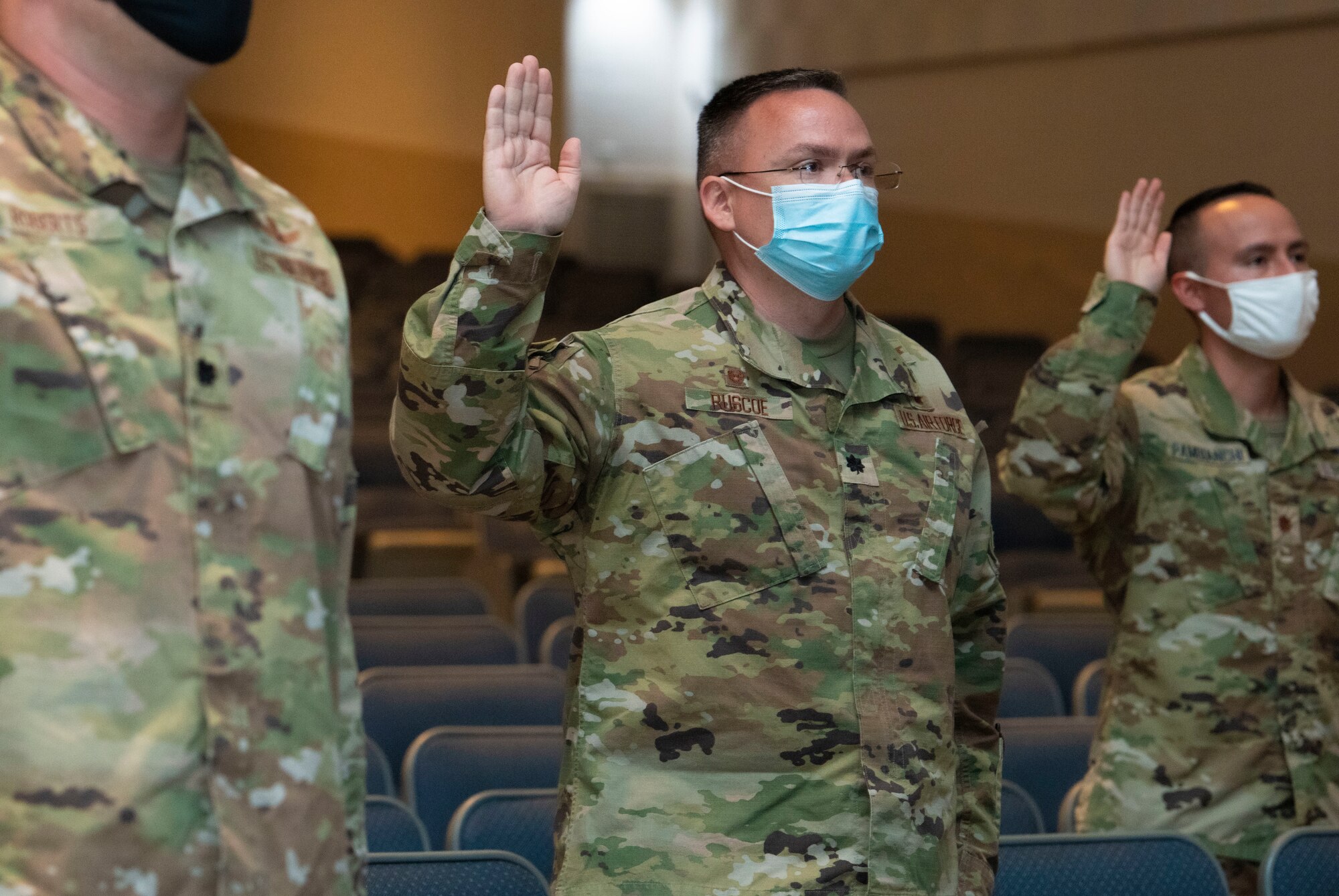 Air Force officers, assigned to Air University, raise their right hand and recite the Oath of Office during a ceremonial swear-in in Polifka Auditorium.