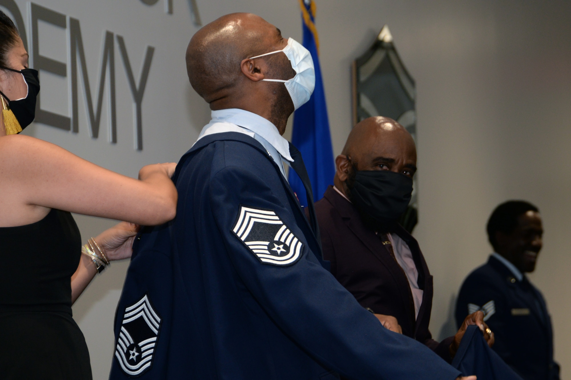 Chief Master Sgt. Howard Dixon dons a service coat with his new rank with the assistance of his wife and father during a promotion ceremony Oct. 3, 2020 at Joint Base San Antonio-Lackland, Texas.