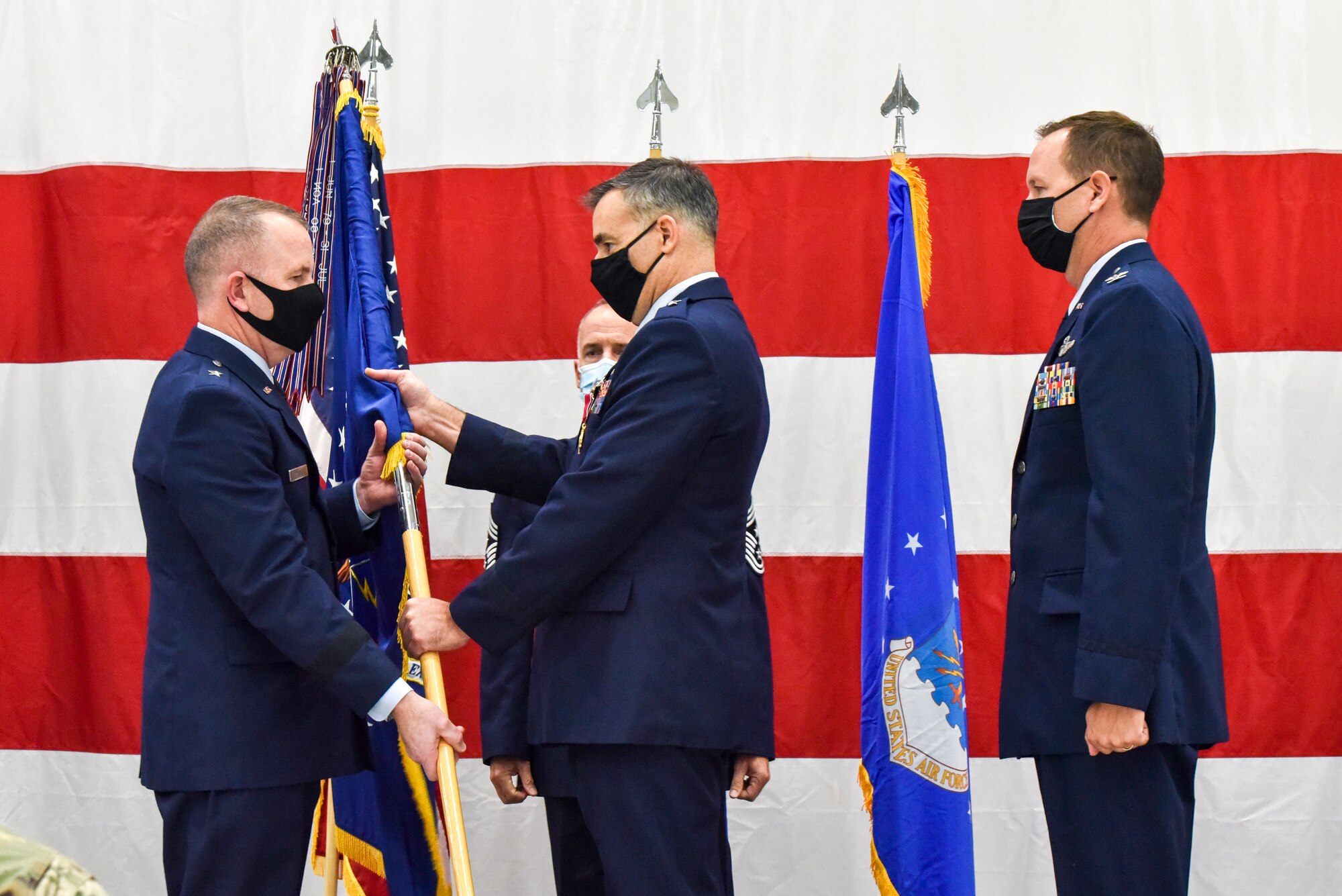 Brig. Gen. Erik Peterson, Chief of Staff, Wisconsin Air National Guard, passes the 115th Fighter Wing unit flag to Brig. Gen. David May, Wisconsin’s deputy adjutant general for Air as part of the official change of command ceremony in an aircraft hangar at the 115th Fighter Wing, Madison, Wis., Oct 3, 2020. Col. Bart Van Roo assumed command of the 115th Fighter Wing from Brig. Gen. Erik Peterson. (U.S. Air National Guard Photo by Tech. Sgt. Mary Greenwood)
