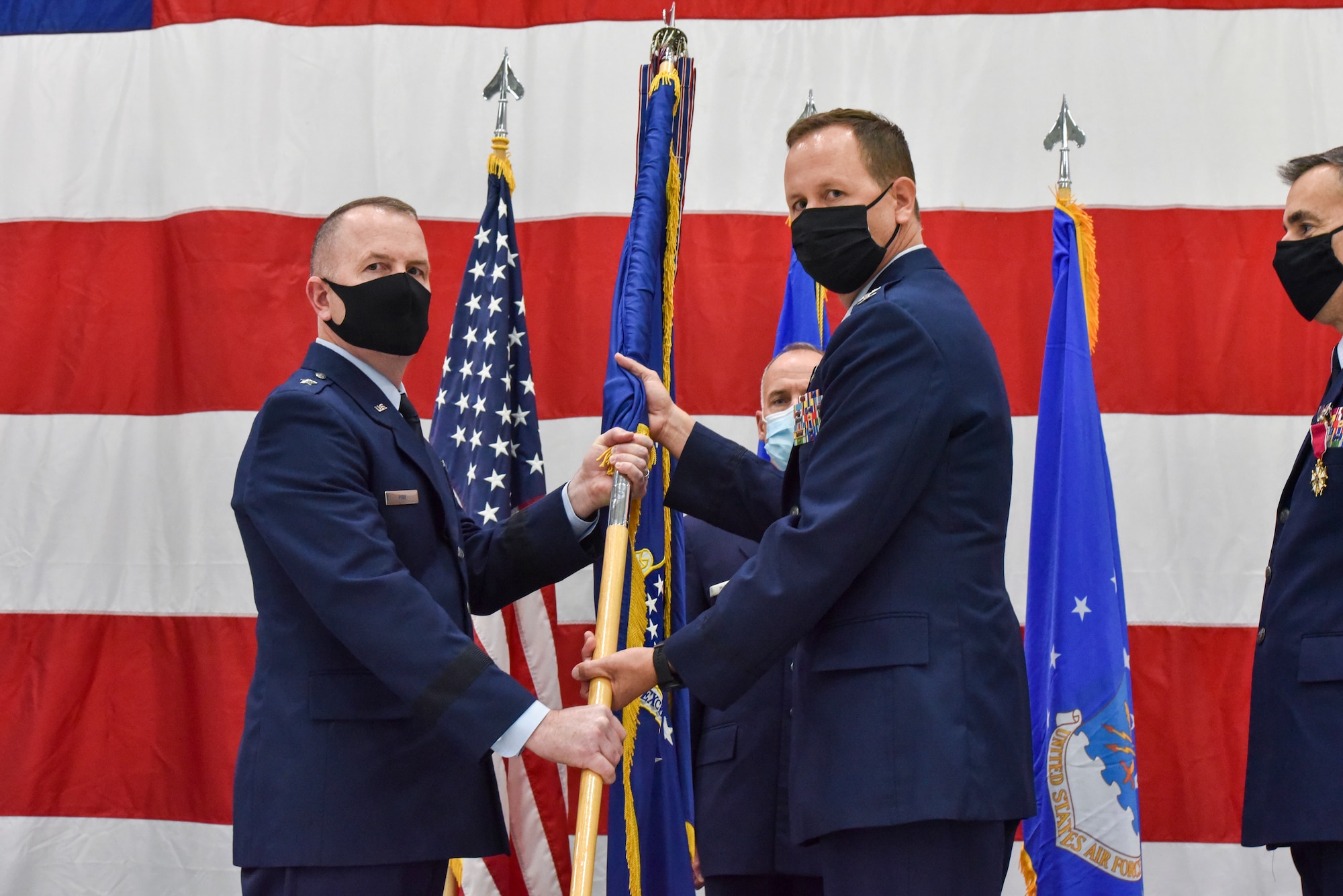 Brig. Gen. David May, Wisconsin’s deputy adjutant general for Air, passes the 115th Fighter Wing unit flag to Col. Bart Van Roo, 115th Fighter Wing commander, who assumed command from Brig. Gen. Erik Peterson, Chief of Staff, Wisconsin Air National Guard, as part of the official change of command ceremony in an aircraft hangar at the 115th Fighter Wing, Madison, Wis., Oct 3, 2020. Col. Bart Van Roo assumed command of the 115th Fighter Wing from Brig. Gen. Erik Peterson. (U.S. Air National Guard Photo by Tech. Sgt. Mary Greenwood)