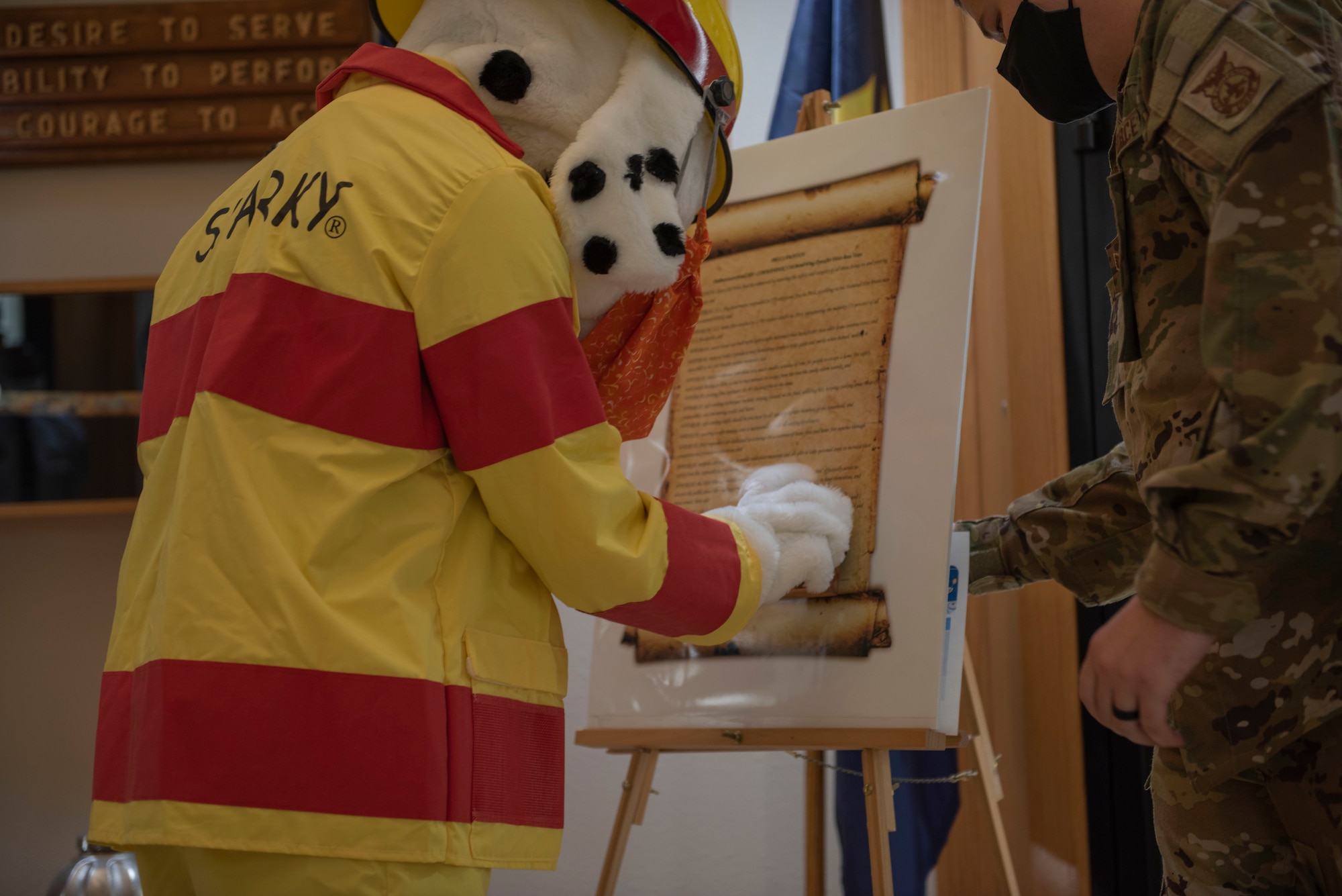 Staff Sgt. Jordan Elkins, 7th Civil Engineer Squadron fire inspector, right, watches as Sparky, 7th CES fire dog, signs a Fire Prevention Week proclamation at Dyess Air Force Base, Texas, Oct. 5, 2020. Fire prevention week is an annual event that is intended to enhance knowledge of fire safety and preparedness. (U.S. Air Force photo by Airman First Class Colin Hollowell)