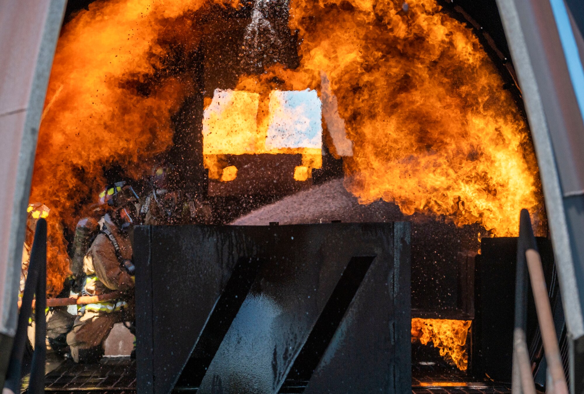 Firefighters from the 436th Civil Engineer Squadron and 177th Civil Engineer Squadron extinguish flames inside an aircraft live-fire trainer during joint training at Dover Air Force Base, Delaware, Sept. 22, 2020. Total Force and civilian fire companies in the surrounding community often partner with Dover AFB to complete annual training requirements. (U.S. Air Force photo by Senior Airman Christopher Quail)