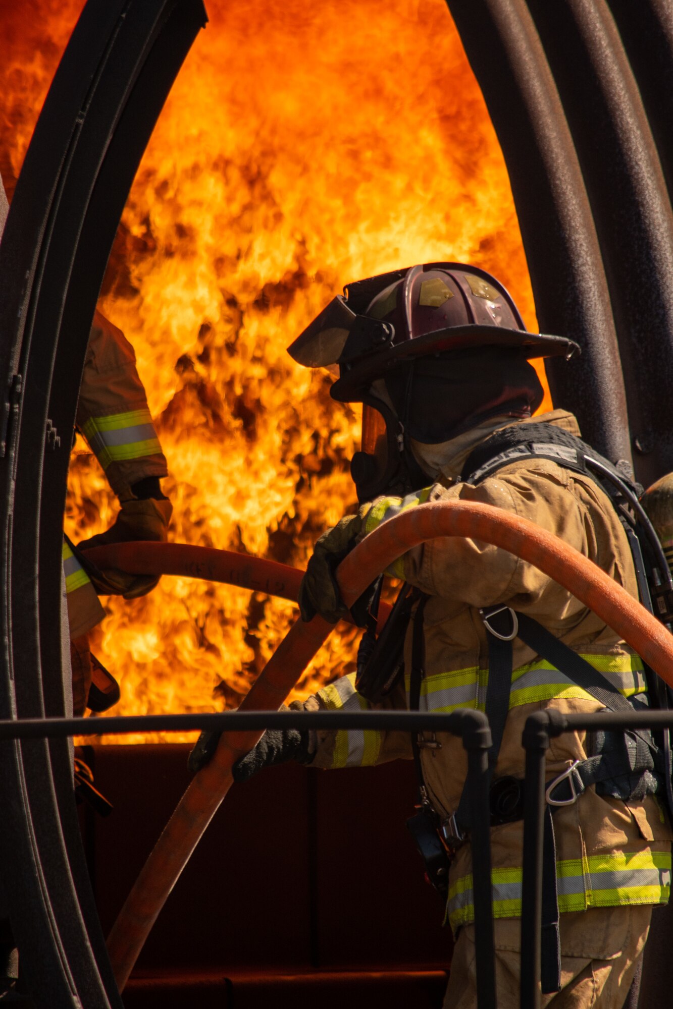 A U.S. Air Force firefighter pulls a fire hose into an aircraft fire trainer during a training exercise at Dover Air Force Base, Delaware, Sept. 22, 2020. Temperatures inside the aircraft fire trainer can reach up to 1,500 degrees Fahrenheit. (U.S. Air Force photo by Airman Brandan Hollis)